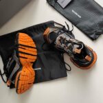 Scarpe sportive di lusso Balenciaga con borse nere e dettagli arancioni.