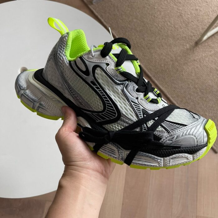 Sneaker sportiva moderna grigia con dettagli neon verdi, suola antiscivolo e riflettente, perfetta per running.