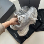 Sneakers grigie eleganti con suola chunky, scatole di lusso e borsa pratica, stile moderno e innovativo.