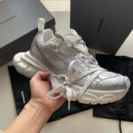 Sneaker bianca di design moderno con dettagli metallici, packaging di lusso e stile urbano sofisticato.