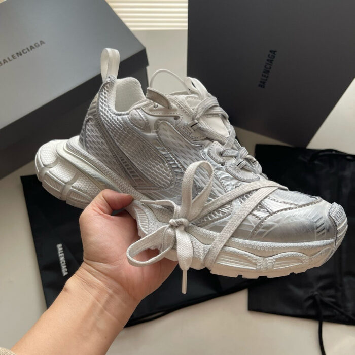 Sneaker bianca di design moderno con dettagli metallici, packaging di lusso e stile urbano sofisticato.