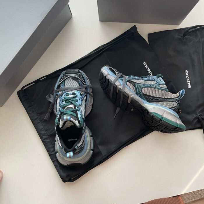 Scarpe sportive eleganti nere e grigie con dettagli teal, presentate su borsa raffinata e scatole minimaliste.
