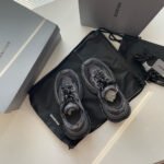 Sneaker nere di lusso con scatole eleganti e stile moderno.