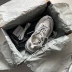 Sneaker di lusso in confezione premium con stoffa, libro e dettagli eleganti.