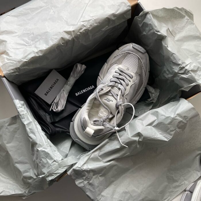 Sneaker di lusso in confezione premium con stoffa, libro e dettagli eleganti.
