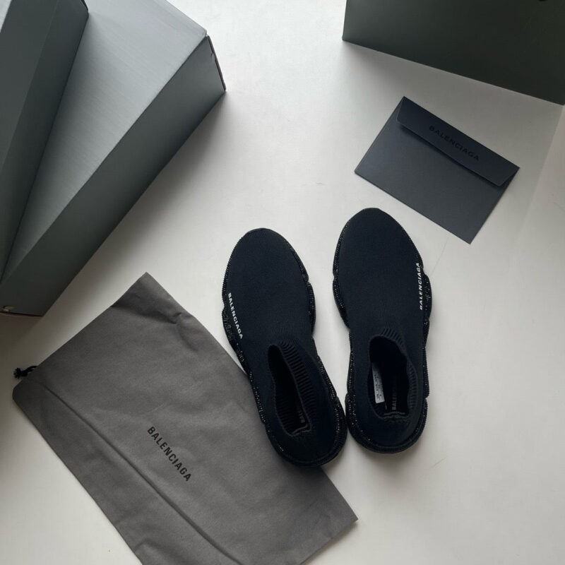 Scarpe slip-on nere di lusso, accessori eleganti e packaging moderno in stile minimalista.