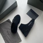 Scarpe nere di lusso in stile moderno, con packaging elegante e dettagli di alta moda.