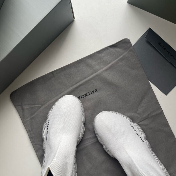 Sneakers minimaliste di lusso con scatola elegante e sacchetto protettivo in un packaging raffinato.