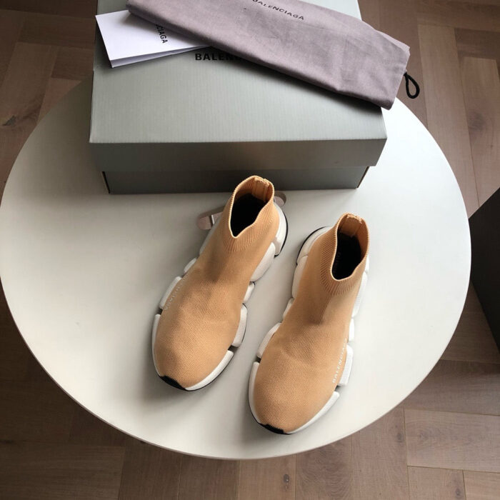 Scarpe da moda beige con suola spessa, scatola minimalista e dust bag su pavimento in legno.