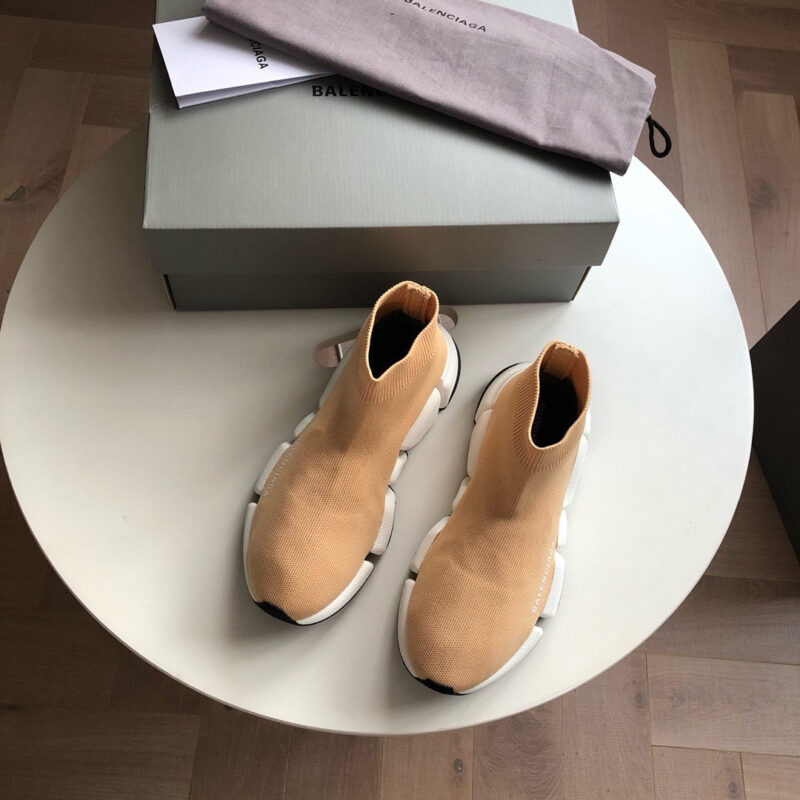 Scarpe da moda beige con suola spessa, scatola minimalista e dust bag su pavimento in legno.