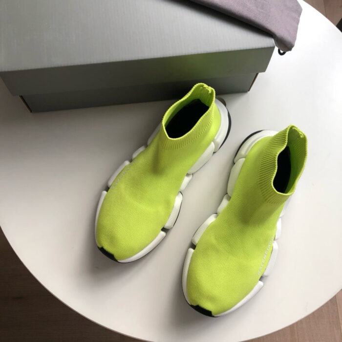 Sneakers neon gialle moderne con suola spessa su tavolo bianco, scatola grigia inclusa.