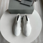 Sneaker bianche moderne minimaliste su tavolo, con scatola elegante e dettagli di stile raffinato.