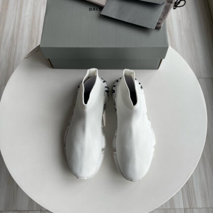 Sneaker bianche moderne minimaliste su tavolo, con scatola elegante e dettagli di stile raffinato.