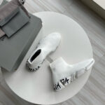 Sneaker moderne con dettagli grafici su tavolino bianco in stile minimal e fashion contemporaneo.