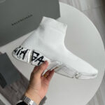 Sneaker Balenciaga bianca con suola trasparente e logo prominente, stile moderno e minimalista.