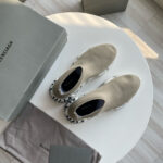 Sneakers Balenciaga nere e beige su tavolo bianco con scatole e dust bag di lusso.