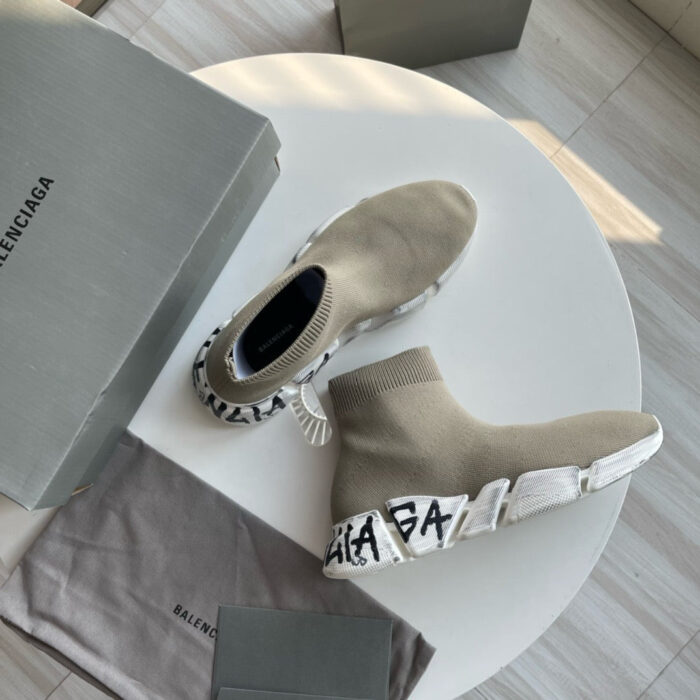 Sneaker Balenciaga moderno in beige su tavolo bianco con scatola e dust bag elegante.