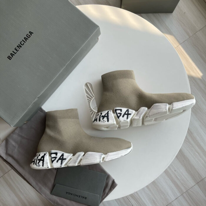 Sneaker Balenciaga high-top beige su tavolo bianco, minimalista ed elegante, con logo nero e scatola.