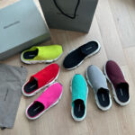 Scarpe slip-on trendy Balenciaga con dettagli colorati su pavimento in legno naturale.