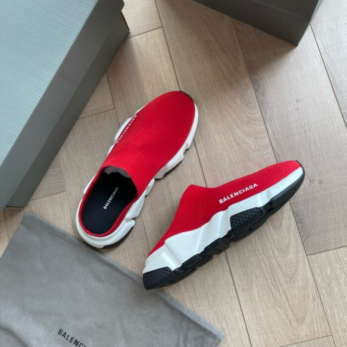 Sneakers Balenciaga rosse moderne su pavimento in legno, stile elegante e urban streetwear.