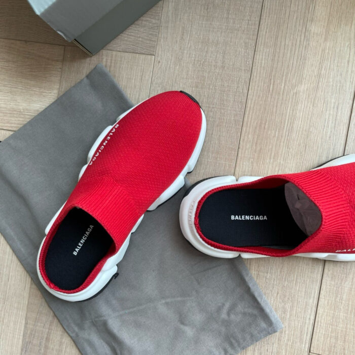 Sneakers Balenciaga rosse in tessuto tecnico con suola bianca, su pavimento in legno.