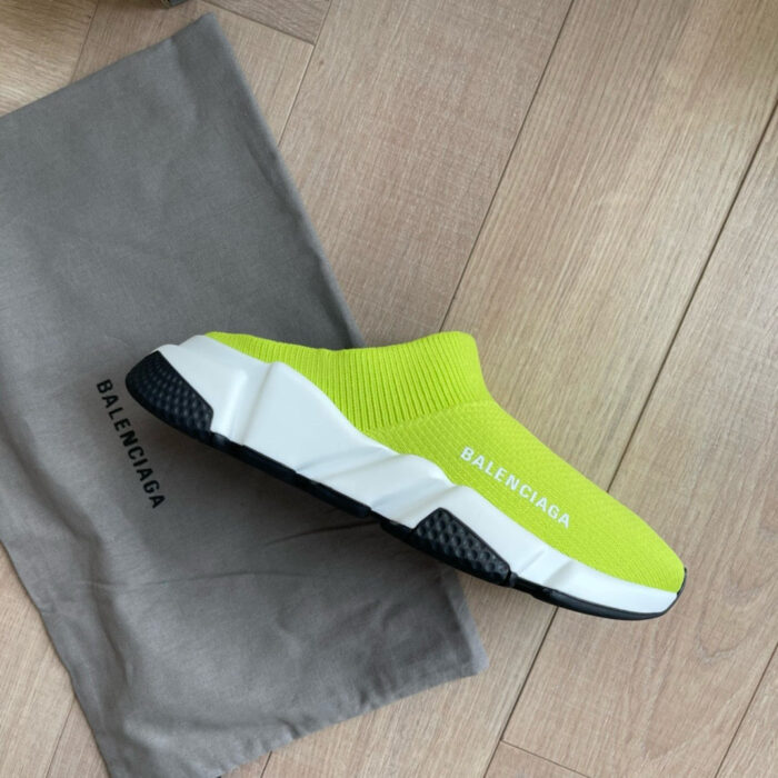 Sneaker neon gialla Balenciaga su pavimento in legno, stile minimalista e bag dustbag inclusa.
