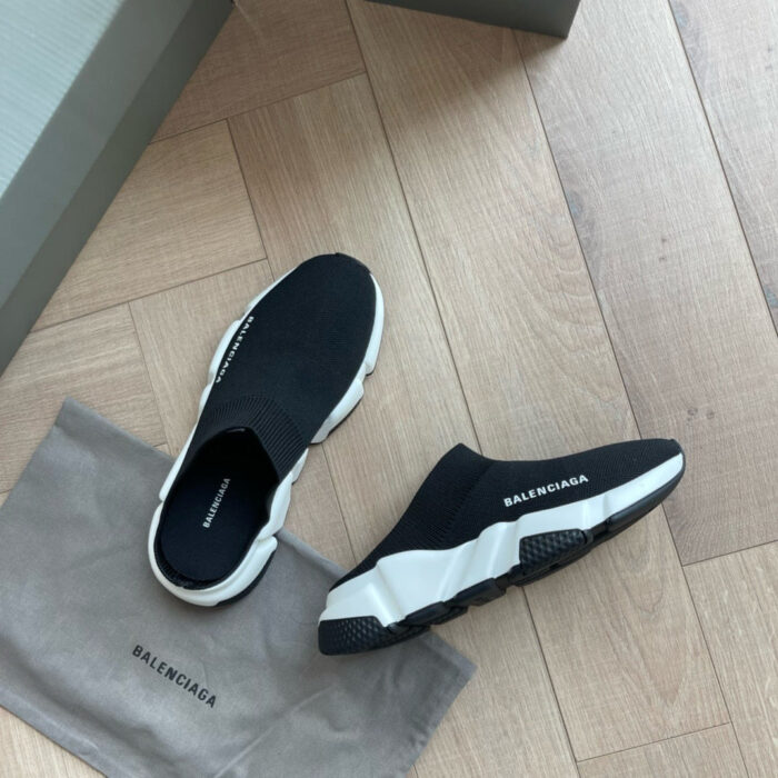 Scarpe Balenciaga minimaliste in bianco e nero su pavimento in legno, stile moderno e di lusso.