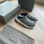 Scarpe Balenciaga slip-on grigie con suola spessa, eleganti e moderne su pavimento di legno.