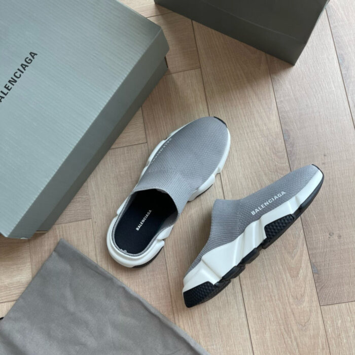 Sneakers Balenciaga in scatola elegante su pavimento in legno chiaro, stile moderno e di lusso.