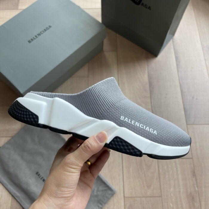 Scarpa slip-on Balenciaga grigia minimalista con logo bianco, elegante e leggera su pavimento di legno.