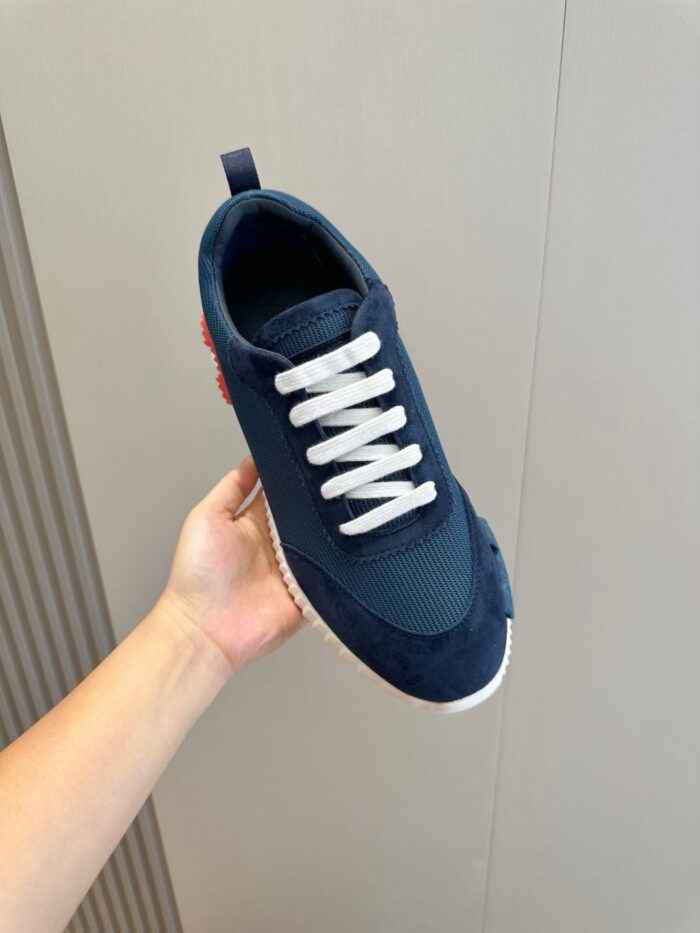 Sneaker moderna in mesh blu navy con dettagli rossi e lacci bianchi, versatile e stile casual.