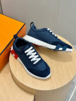 Sneakers navy e bianco con dettagli rossi, stile sportivo e design moderno su tavolo in legno.