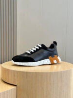 Sneaker moderna nera con dettagli arancioni, su piedistallo in legno, stile elegante e casual.