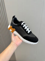 Sneaker nera moderna con dettagli arancioni e suola spessa, stile casual e sportivo elegante.
