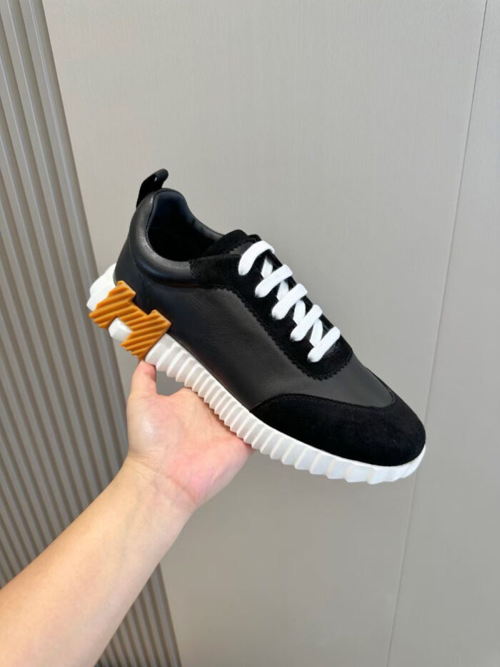 Sneaker nera moderna con dettagli arancioni e suola spessa, stile casual e sportivo elegante.
