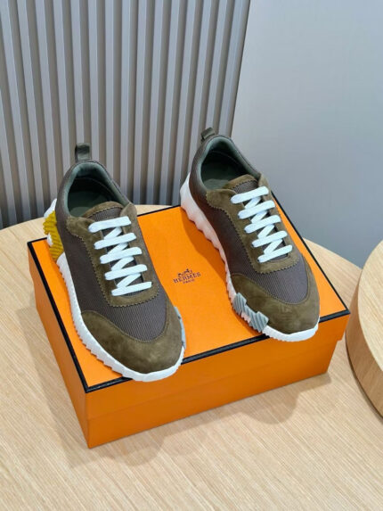 Sneakers di design marrone beige su superficie in legno con scatola arancione elegante.
