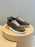Sneakers moderne con dettagli gialli, tonalità terrose e design elegante su pedana di legno.