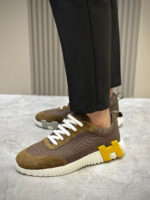 Sneakers marroni con dettagli gialli, lacci bianchi, stile moderno e outfit elegante.