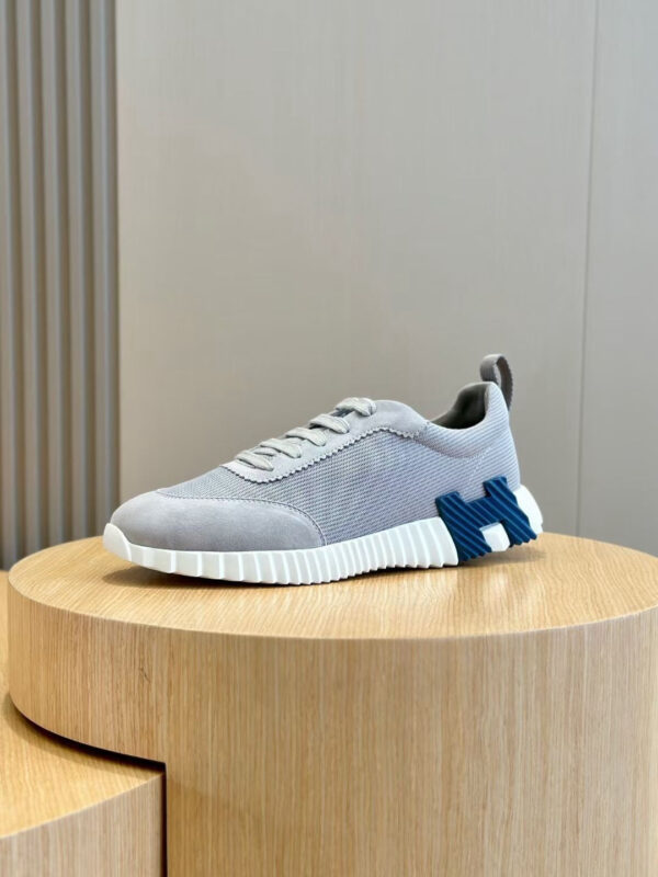 Sneaker moderna grigia con dettagli blu e suola spessa, perfetta per stile casual e urbano.