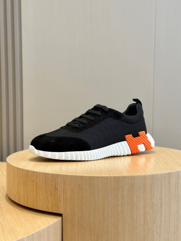 Sneaker nera con dettaglio arancione e suola moderna, stile streetwear e performance.