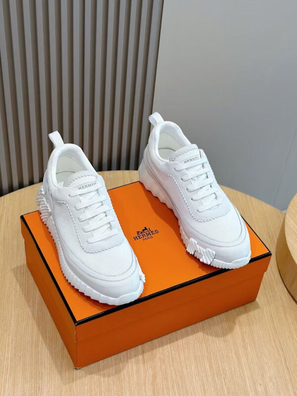 Sneakers bianche di tendenza su scatola arancione lucida, stile moderno e comfort premium.