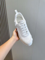 Sneaker bianca moderna, minimalista e resistente, tenuta in mano su sfondo luminoso.
