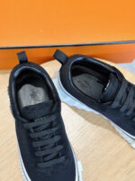 Scarpe sportive nere con suola bianca su sfondo arancione vibrante.