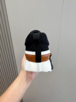 Sneaker sportiva nera con suola bianca e dettaglio marrone sul tallone.