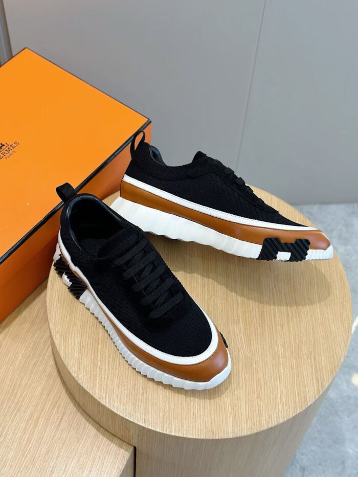 Sneakers moderne neri con suola bianca e dettagli marroni su stand di legno.