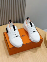 Scarpe sportive bianche con dettagli arancioni su scatola elegante, stile moderno e di lusso.