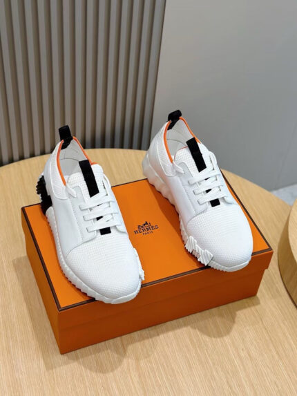 Scarpe sportive bianche con dettagli arancioni su scatola elegante, stile moderno e di lusso.