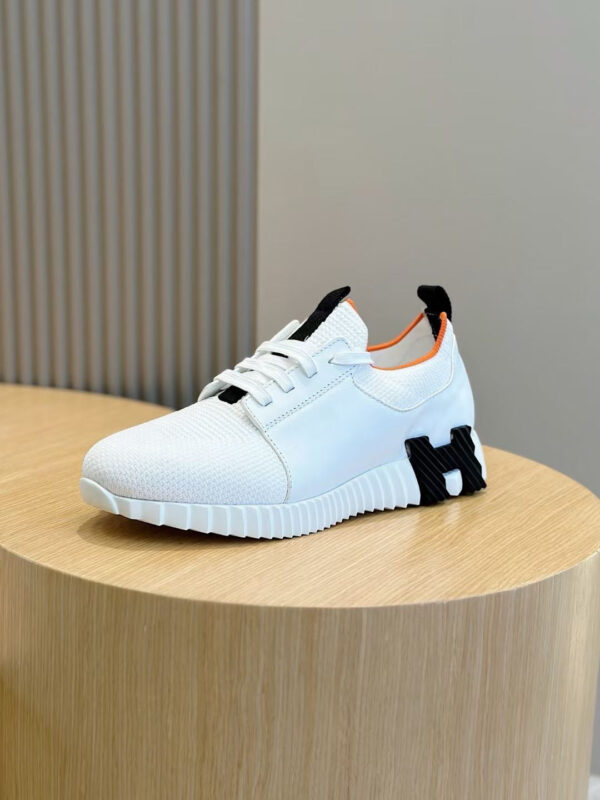 Scarpa sneakers bianca moderna con dettagli nero e arancione, elegante e versatile.