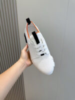 Scarpa sportiva bianca con dettagli arancioni, comfort, stile minimalista e design moderno.