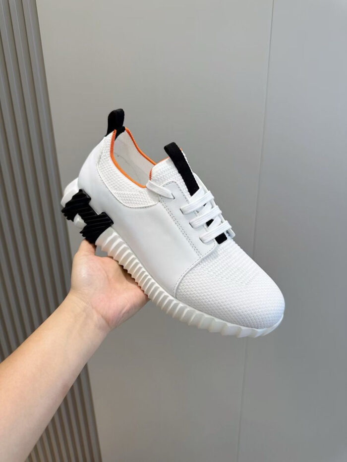 Sneaker bianca moderna con dettagli arancioni, suola antiscivolo e design minimalista.